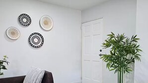 A living room with a dark brown sofa, a potted plant, and four wall-mounted circular wall decorations.