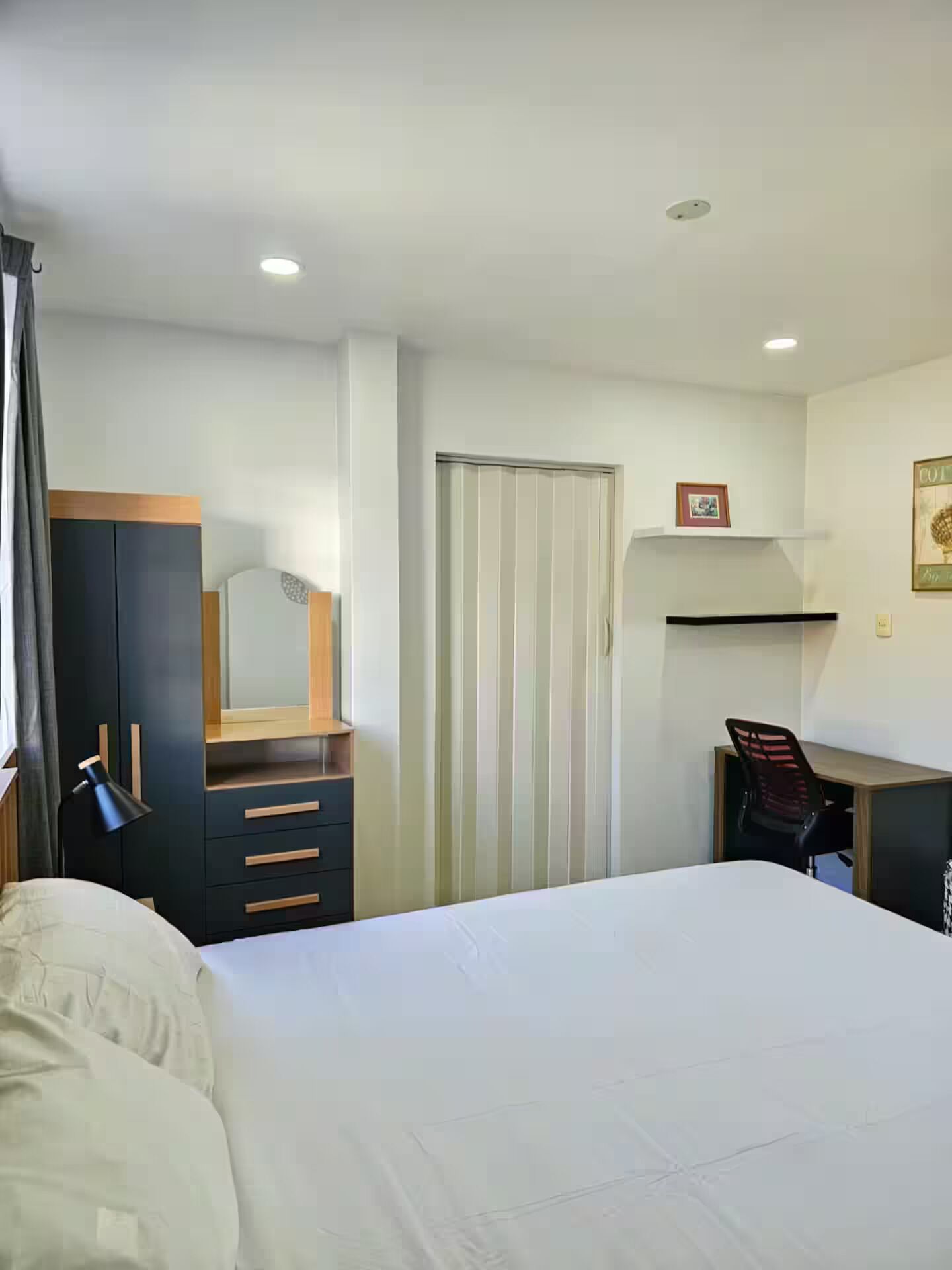 Una habitación de hotel con cama, escritorio, silla, armario y puerta.