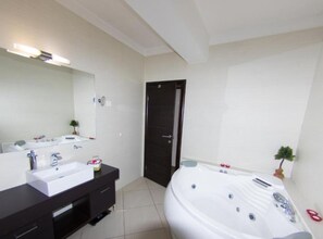 A modern bathroom with a large white bathtub, a double sink vanity, and a dark door. - One Bedroom Apartment With Terrace (Opatija)