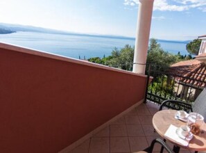 A balcony with a table set for two, overlooking a scenic view of the sea. - One Bedroom Apartment With Terrace (Opatija)