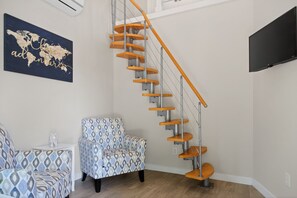 A modern interior with a spiral staircase, patterned armchairs, and a world map artwork. - Casita w/ Outdoor Shower, Near Main + Wineries! (Fredericksburg)