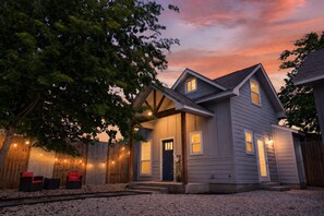 A two-story house with a front porch, a wooden fence, and string lights. - Casita w/ Outdoor Shower, Near Main + Wineries! (Fredericksburg)