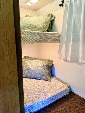 Un lit superposé avec une literie à motifs, un rideau et un cadre de porte en bois.