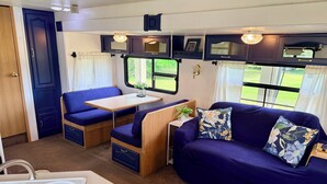 A compact RV interior with a dining area, seating, and a sink. - 2-bedroom waterfront camper in welcoming Decaturville with AC for relaxing stays (Decaturville)
