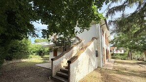 Eine Steintreppe führt zu einem weißen Gebäude mit hölzernem Geländer und einer kleinen Veranda.