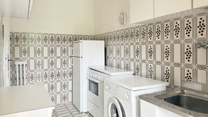 Eine kleine Küche mit Waschmaschine, Kühlschrank und Spüle.