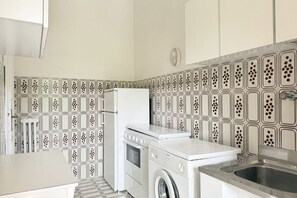 Eine kleine Küche mit Waschmaschine, Kühlschrank und Spüle.
