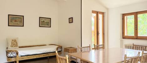 A room with a bed, a dining table with chairs, and framed pictures on the wall.
