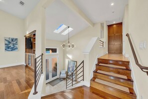 A spacious interior with a wooden staircase, a ceiling with skylights, and a modern light fixture. - Walk to the Shore from This Point Richmond Escape (Richmond)