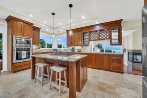 A modern kitchen with wooden cabinets, a large island, stainless steel appliances, and a view of the outdoors. - Walk to the Shore from This Point Richmond Escape (Richmond)