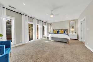 A bedroom with a large bed, a ceiling fan, a nightstand, a mirror, and a sliding glass door leading to a balcony. - Walk to the Shore from This Point Richmond Escape (Richmond)