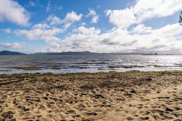 A sandy beach with waves, distant mountains, and a ship in the background. - Walk to the Shore from This Point Richmond Escape (Richmond)
