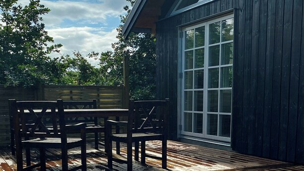Eine Holzterrasse mit Stühlen, einem Holzzaun und einem großen Fenster.