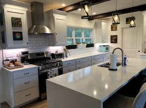 Une cuisine moderne avec des meubles blancs, un grand îlot central, une cuisinière et une machine à café.