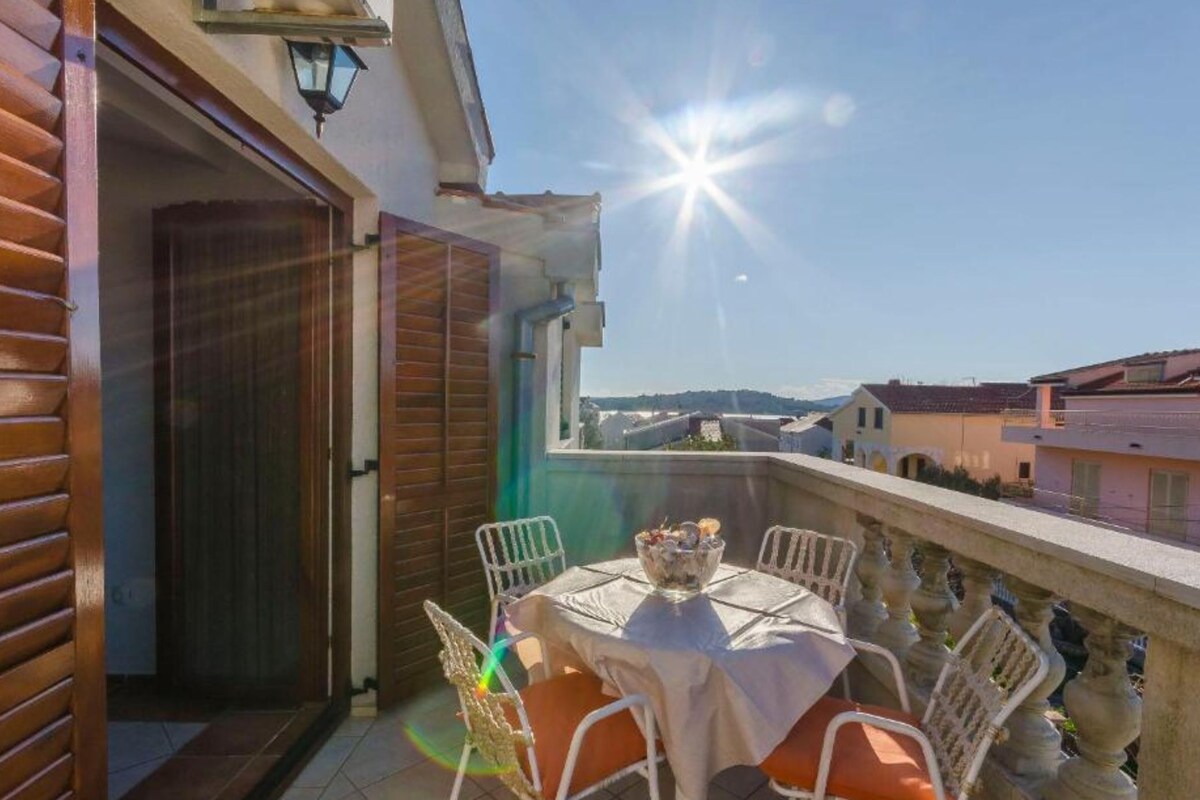 A balcony with a table and chairs, a view of the city, and a clear sky.