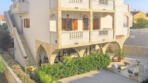 A multi-story building with balconies, a satellite dish, and a stone base. - Villa Estella Adriatic Residence (Vodice)