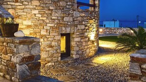 Un bâtiment en pierre doté d’une porte d’entr ée, d’un petit jardin agrémenté de galets et offrant une vue sur la mer en arrière-plan.