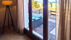 A room with a sliding glass door leading to an outdoor area with a pool and a view of the sea. - PetraCasa: Luxury Sea View Villa with Premium Private Outdoor Spa (Azolimnos)