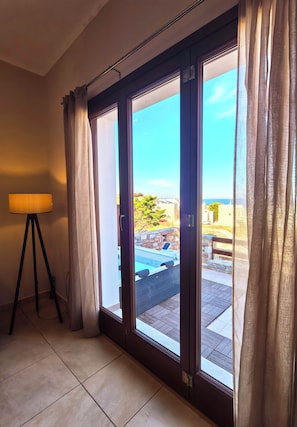 Ein Zimmer mit einer Schiebetür zu einem Außenbereich mit Pool und Meerblick.