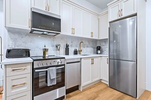 Una cocina moderna con armarios blancos, electrodomésticos de acero inoxidable y suelo de madera.