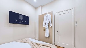 Ein Hotelzimmer mit einem Bett, einem an der Wand hängenden Bademantel und einer Tür.