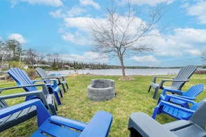 Mobiliario exterior con sillas Adirondack, un brasero y vistas a un lago.