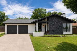 A modern two-story house with a stone facade, a front porch, and two garage doors. - Home with Water Views Near
DFW, Arlington Stadiums (Irving)
