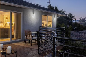 Eine überdachte Terrasse mit Esstisch, Stühlen und Geländer.