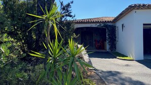 A building with a tiled roof, a driveway, and a garden with various plants. - VILLA NEAR THE BEACHES OF PAMPELONE (Ramatuelle)