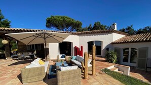 An outdoor patio area with wicker furniture, a large umbrella, and a cactus sculpture. - VILLA NEAR THE BEACHES OF PAMPELONE (Ramatuelle)