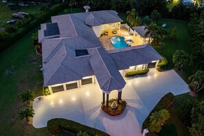 Ein großzügiges Haus mit Swimmingpool, überdachter Terrasse und einem gepflegten Rasen.