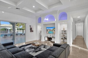 Ein geräumiges Wohnzimmer mit Blick auf einen Pool, einem Flachbildfernseher und einer modernen Gestaltung.