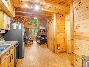 Ein Holzblockhaus-Innenraum mit Küche, Essbereich und Kamin.