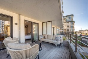 Een balkon met rieten meubels, een bank en een klein tafeltje.
