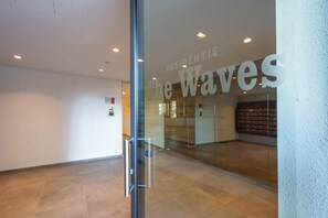 A modern interior with a glass door leading to a lobby area. - Sand & Sail (Ostend)