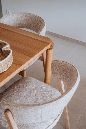 A wooden dining table with woven chairs and a woven basket on it. - Sand & Sail (Ostend)