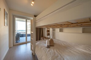A room with a bunk bed, a door leading to a balcony, and a view of the outside. - Sand & Sail (Ostend)