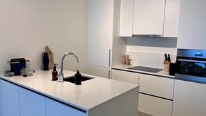 A modern kitchen with white cabinetry, a central island, and a built-in oven.