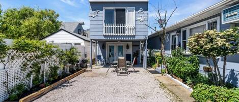 A two-story house with a balcony, a gravel driveway, and a fenced backyard.