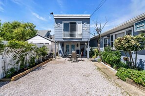 Ein zweistöckiges Haus mit Balkon, einem Schotterweg und einem eingezäunten Garten.