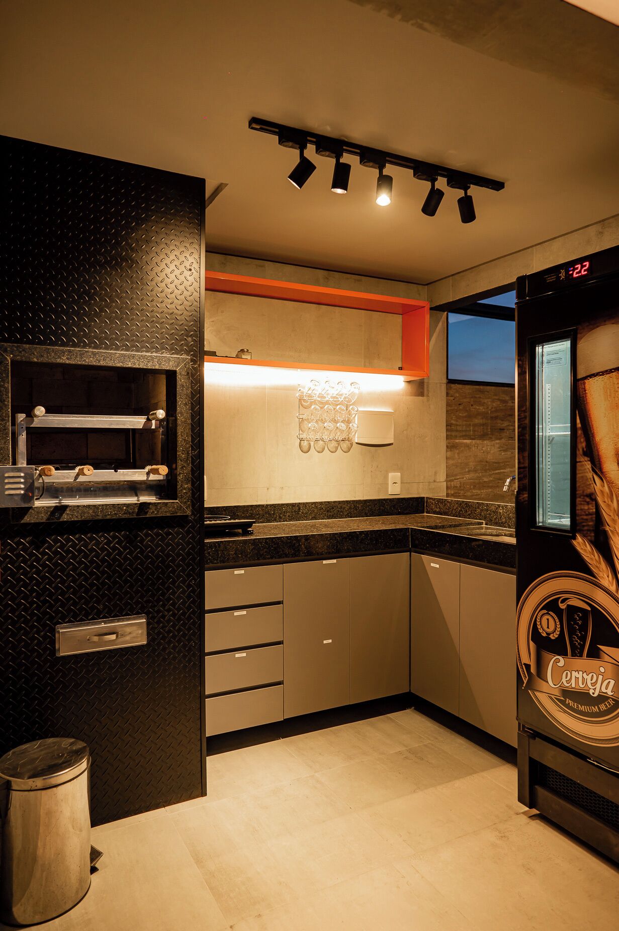 Een moderne keuken met een inbouwoven, een koffieapparaat en een koelkast met een biereadvertentie.