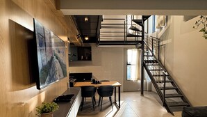 A modern kitchen with a dining area, a staircase, and a flat-screen TV mounted on the wall. - Exclusive Loft | Rooftop with Panoramic Views (São Raimundo Nonato)