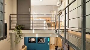 A modern interior with a bed, a blue accent wall, and a staircase leading to an upper level. - Exclusive Loft | Rooftop with Panoramic Views (São Raimundo Nonato)