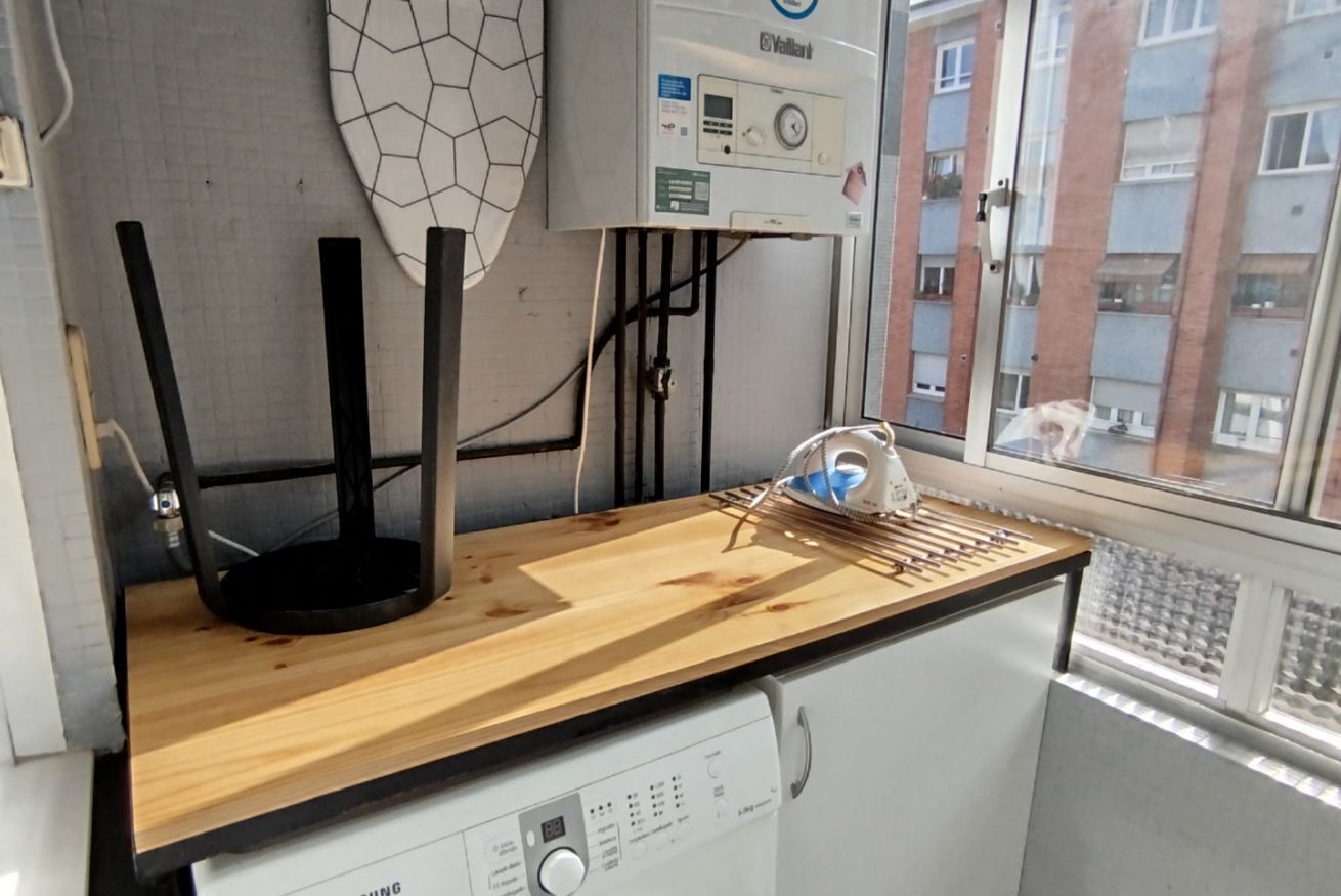 A kitchen with a wooden countertop, a black stand, and a water heater.