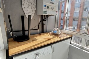 Eine Küche mit einer Holzausziehtheke, einem schwarzen Standgerät und einem Durchlauferhitzer.