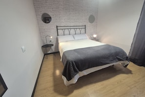 A bedroom with a bed, a nightstand, a wall-mounted light, and a brick-patterned wall. - 1A154 Gijón like at home Apartment for 5 pax (Gijón)