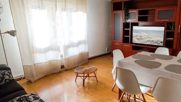 A living room with a TV, a dining table, and a sofa.