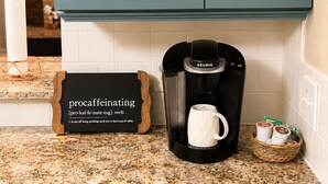 A kitchen with a coffee maker, a mug, and a sign with a coffee-related pun. - Modern 3 Story Home 9 Min to DFW w King Suite Pool (Euless)