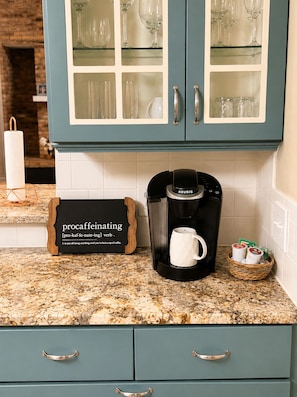 Eine Küche mit Kaffeemaschine, einer Tasse und einem Schild mit einem Kaffeewitz.