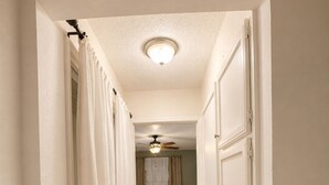 A narrow hallway leading to a bedroom with a bed, a ceiling fan, and a patterned rug. - Modern 3 Story Home 9 Min to DFW w King Suite Pool (Euless)